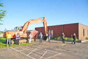 Image of a construction equipment outside Holy Trinity Lutheran Church with individuals spaced out, wearing face mask and hard hats.