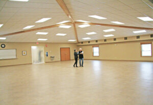 A large open room with a couple dancing in the middle 
